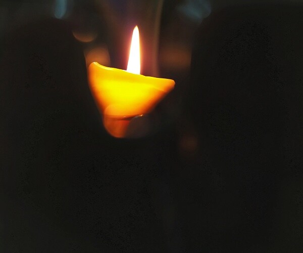 a candle burns in a blurry and dark background