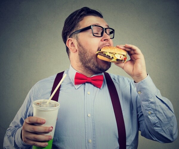 man eating a fast food burger and drinking soda