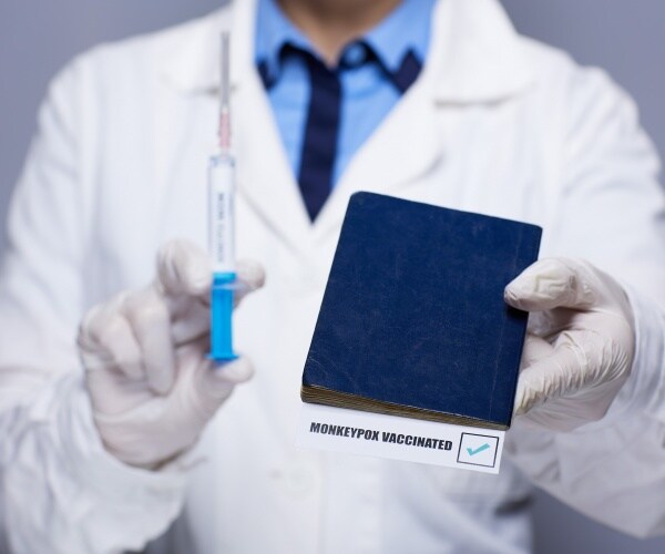 healthcare worker holding a monkeypox vaccine, syringe, and vaccination record