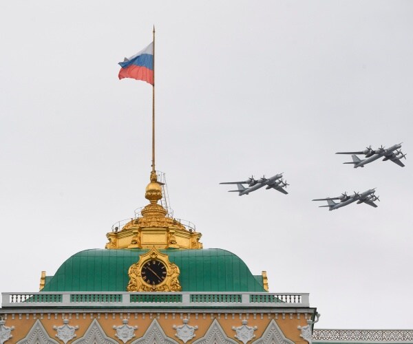 russian bombers in the sky near a building with a russian flag flying over it