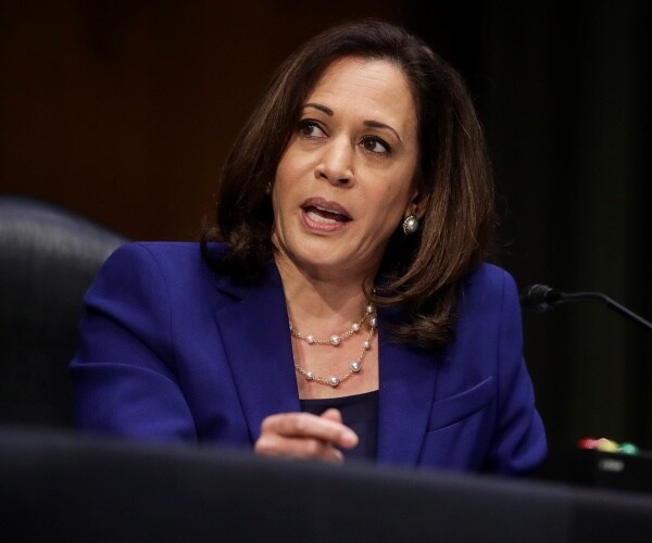 harris in a cobalt blue blazer and black top with a pearl necklace and earrings