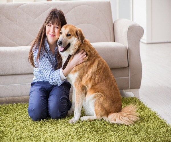 woman at home hugging dog with smile on her face