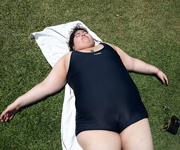 an overweight girl in a speedo lays on her back sleeping