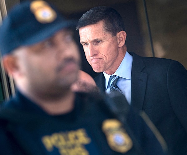 michael flynn grimaces in focus in the background with a police officer blurred out in the foreground