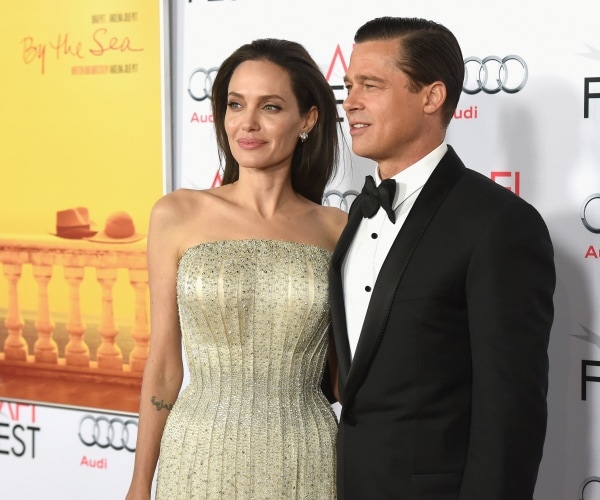 jolie in a light yellow sparkly dress and pitt in a black suit and bow tie