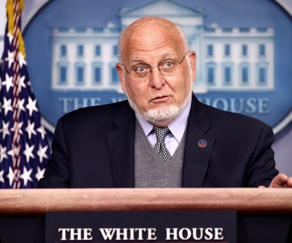 robert redfield stands behind podium in briefing room