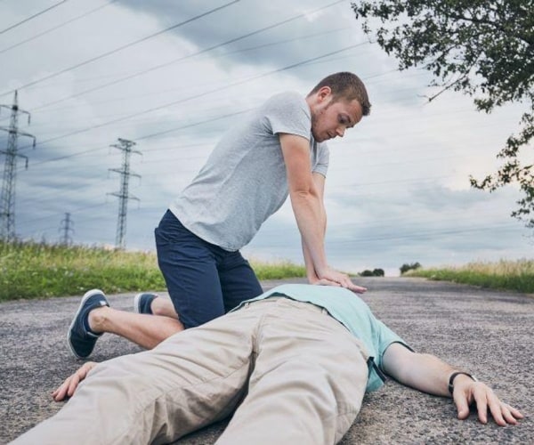 man doing cpr on a man on the street