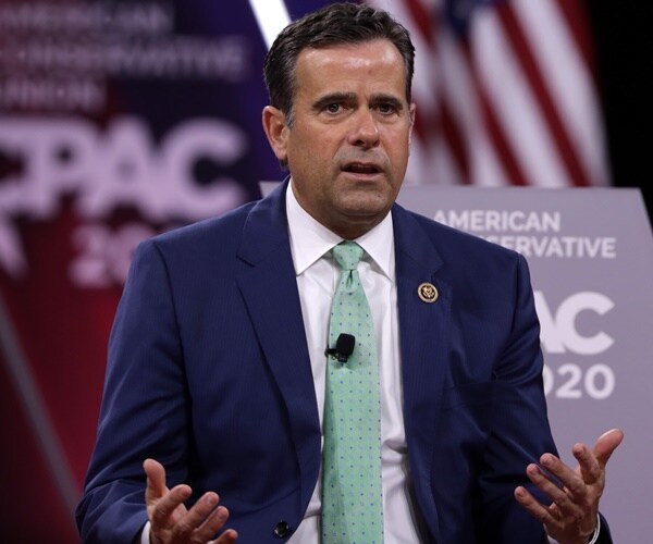 john ratcliffe sits on a stage at cpac and speaks