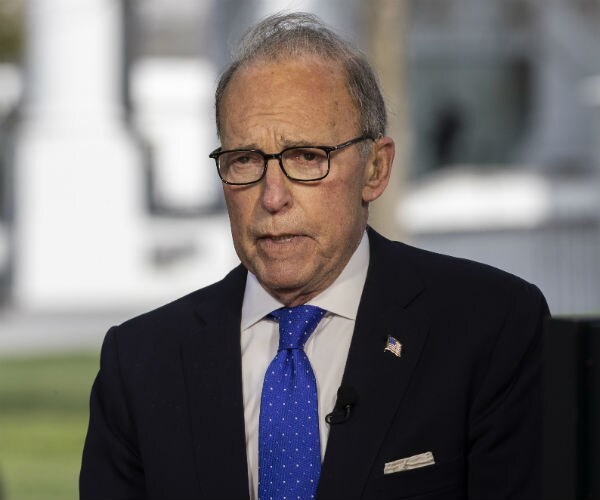 larry kudlow is shown in suit, dress shirt and blue tie speaking to the media