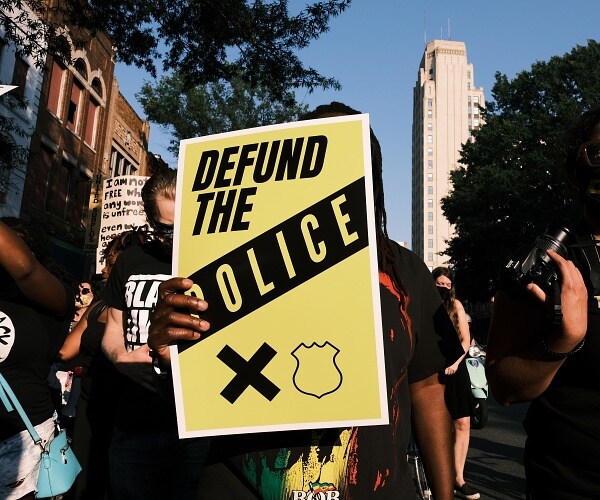 protester holds sign that says defund the police