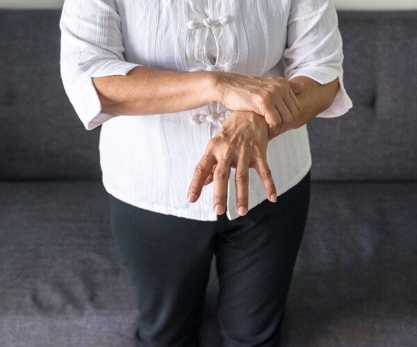 older woman holding her hand with tremors from Parkinson's disease