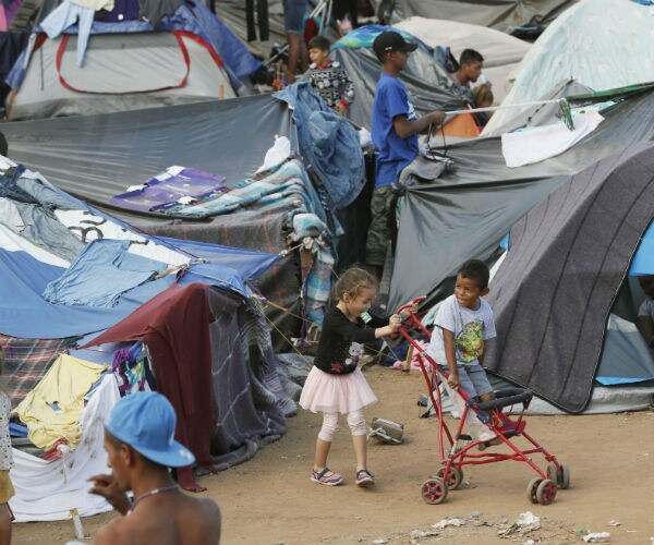 children play amid crowded tents