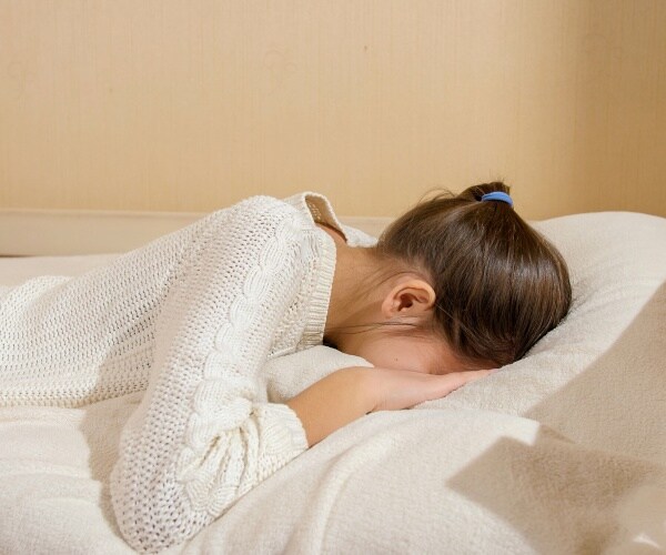 teenager in bed, face down on pillow