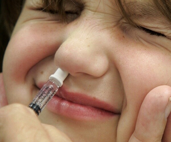 adult administering AstraZeneca nasal flu vaccine to child