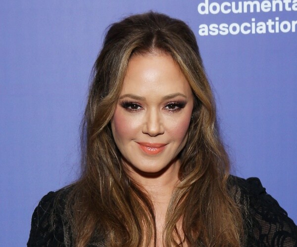 leah remini in a black top in front of a purple background