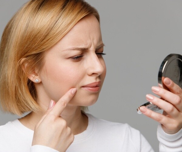 woman looking at her face with handheld mirror