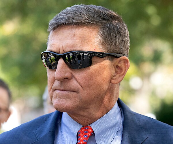 michael flynn stands stone faces outdoors wearing dark sunglasses