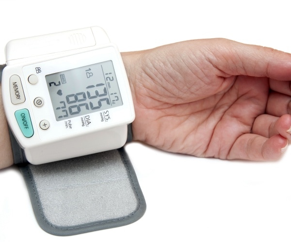 person wearing a blood pressure monitor on wrist with a reading of slightly high blood pressure