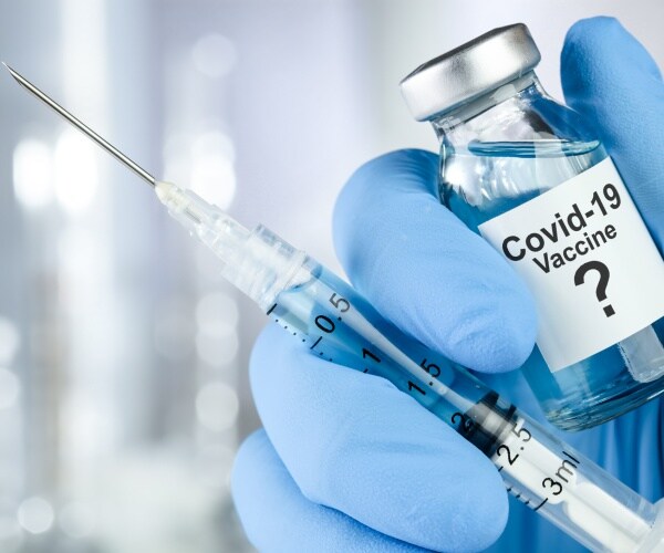 covid-19 vaccine is shown in a glass bottle with a syringe