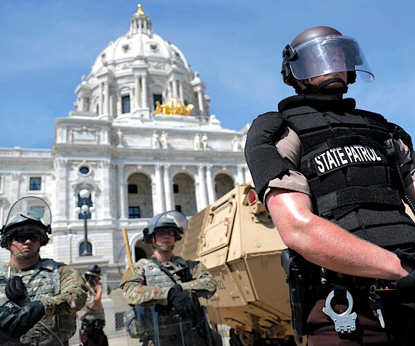 the national guard stands being a police officer in riot gear