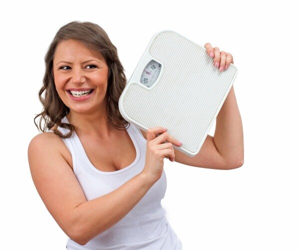 woman holding scale happy that she lost weight