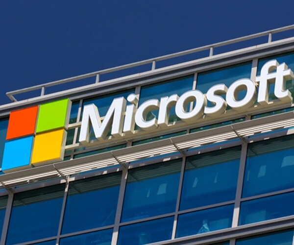 microsoft corporate logo symbol atop building amid blue sky