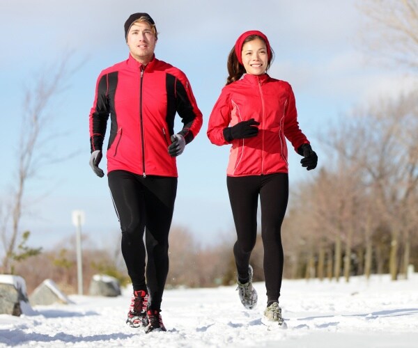 man and woman running outside in snow