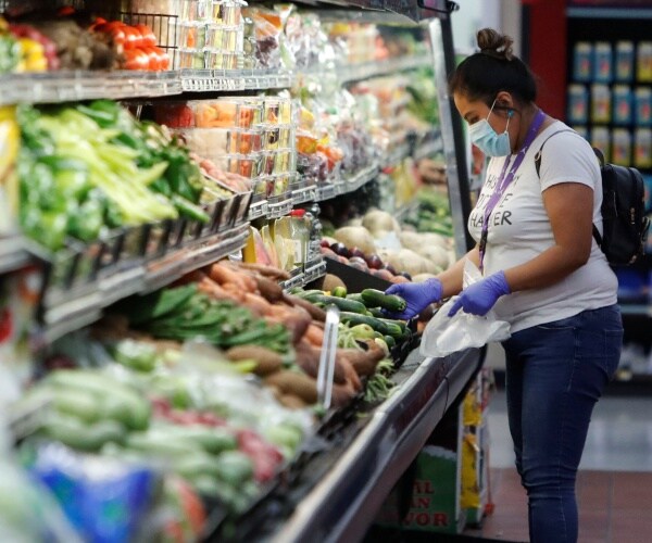 woman wearing a mask in the produce section of a grocery store