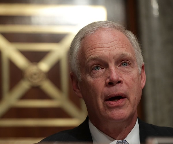 ron johnson speaks in front of a gold inlayed paneled wall.