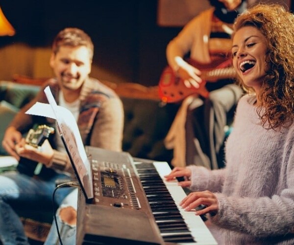 woman playing keyboard, man playing guitar