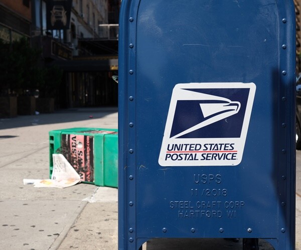 a usps mailbox on a dirty sidewalk in new york city