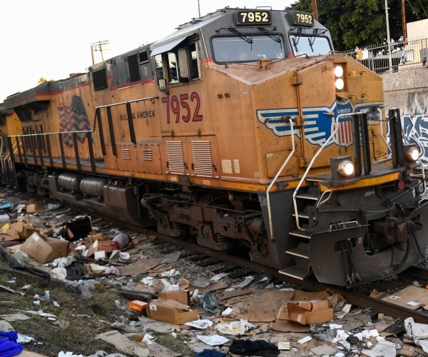 A Union Pacific train passes through a section of tracks littered with garbage.