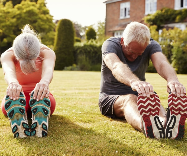 a senior couple stretching outside their home