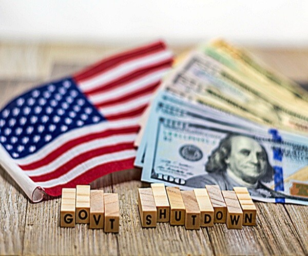 government shutdown usa concept with american flag and money bills on white background and wooden board.

