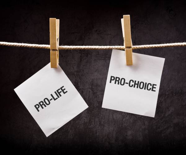 signs reading pro-life and pro-choice hung from a rope with clothespins