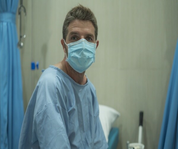 Young adult man in hospital with mask looking at camera