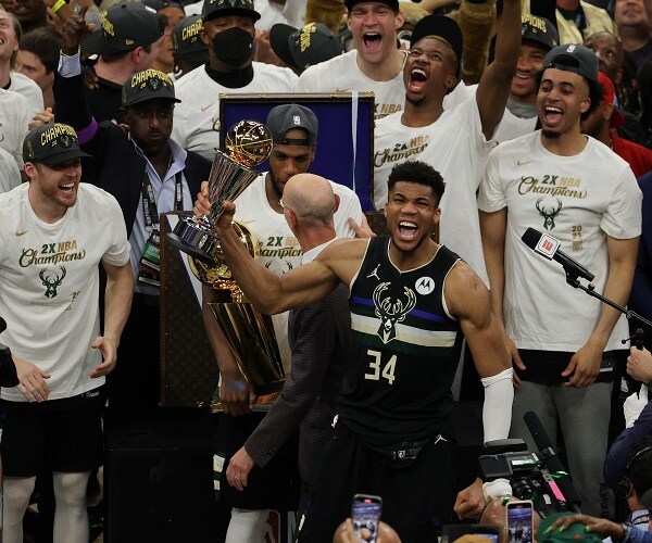 giannis antetokounmpo holds up trophy on crowded basketball court