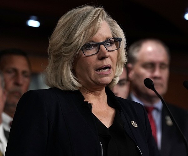 liz cheney speaks with many men standing behind her