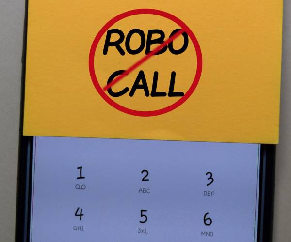 cell phone with a sticky note reading no robocalls