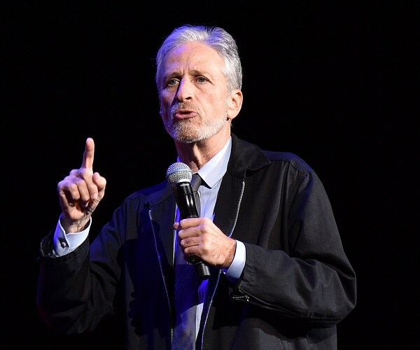 jon stewart speaks into mic onstage