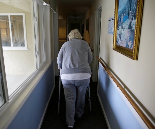 an older woman walking down hall with walker