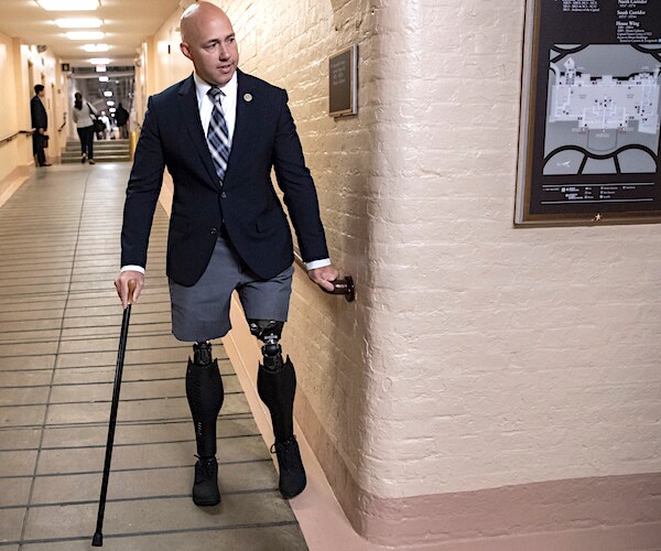 florida republican representative brian mast walks down a hallway on two artificial legs