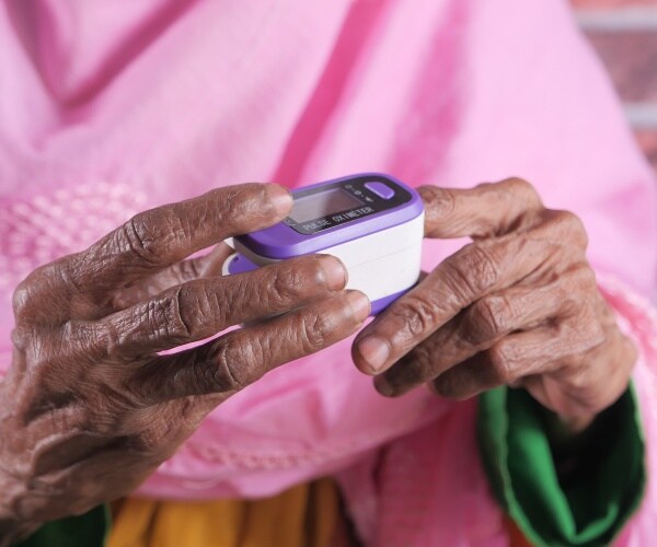 an older black woman's hands, using a pulse oximeter