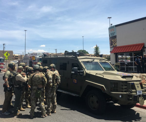 Armed Policemen gather next to an FBI armoured vehicle