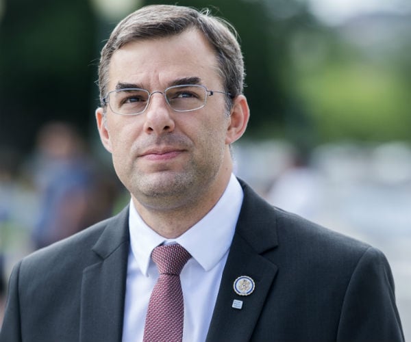 rep. justin amash is shown wearing glasses, suit with white dress shirt.