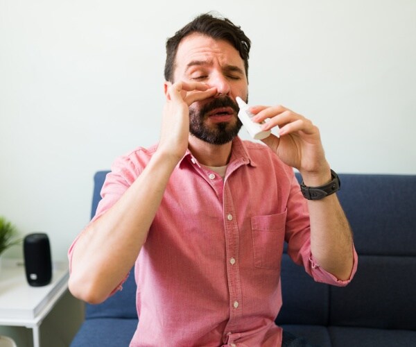 man spraying nose with nasal spray