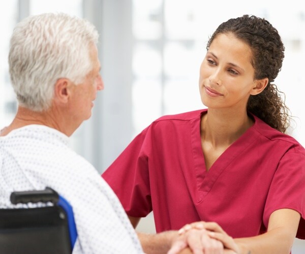 healthcare worker calms older hospital patient in wheelchair