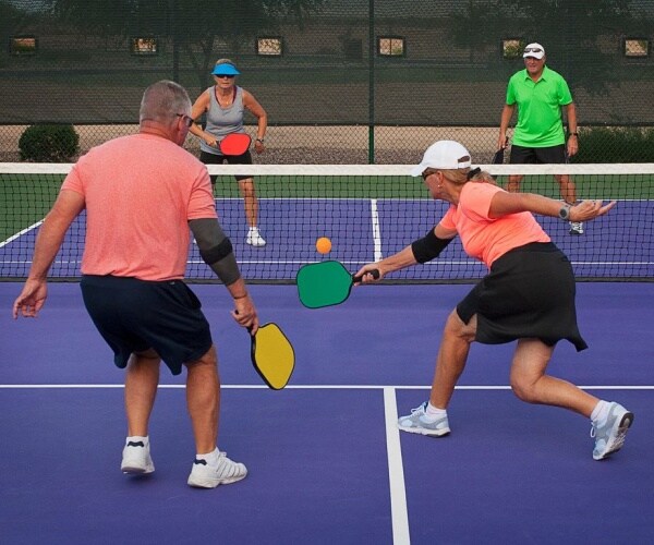 two older adult couples playing pickleball