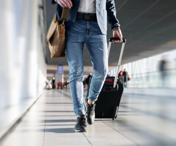 man walking in airport corridor with luggage