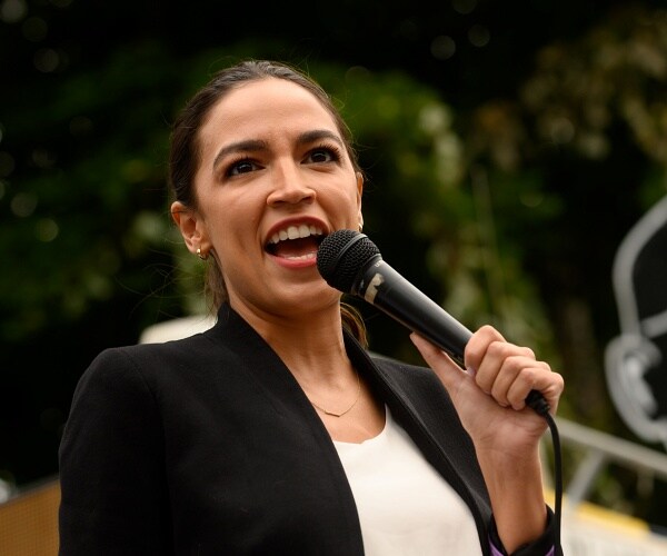 alexandria ocasio cortez speaks into handheld mic